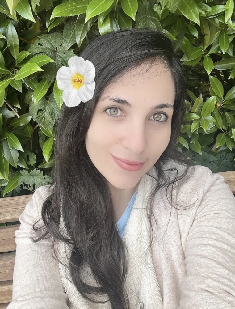 Portrait von Yara vor grünen Pflanzen in einer freundlichen Outdoor-Szene